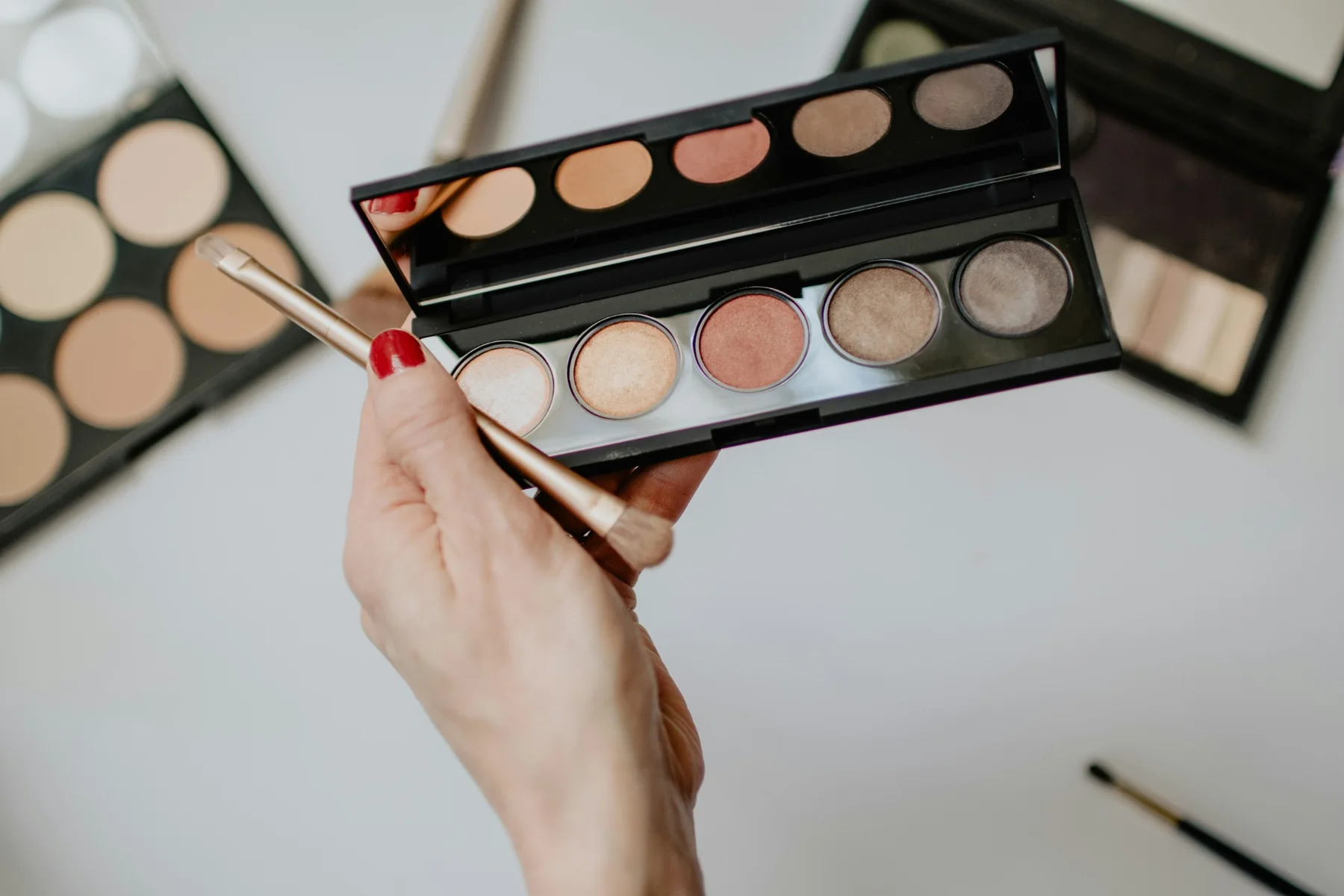 Hand holding a neutral-toned eyeshadow palette