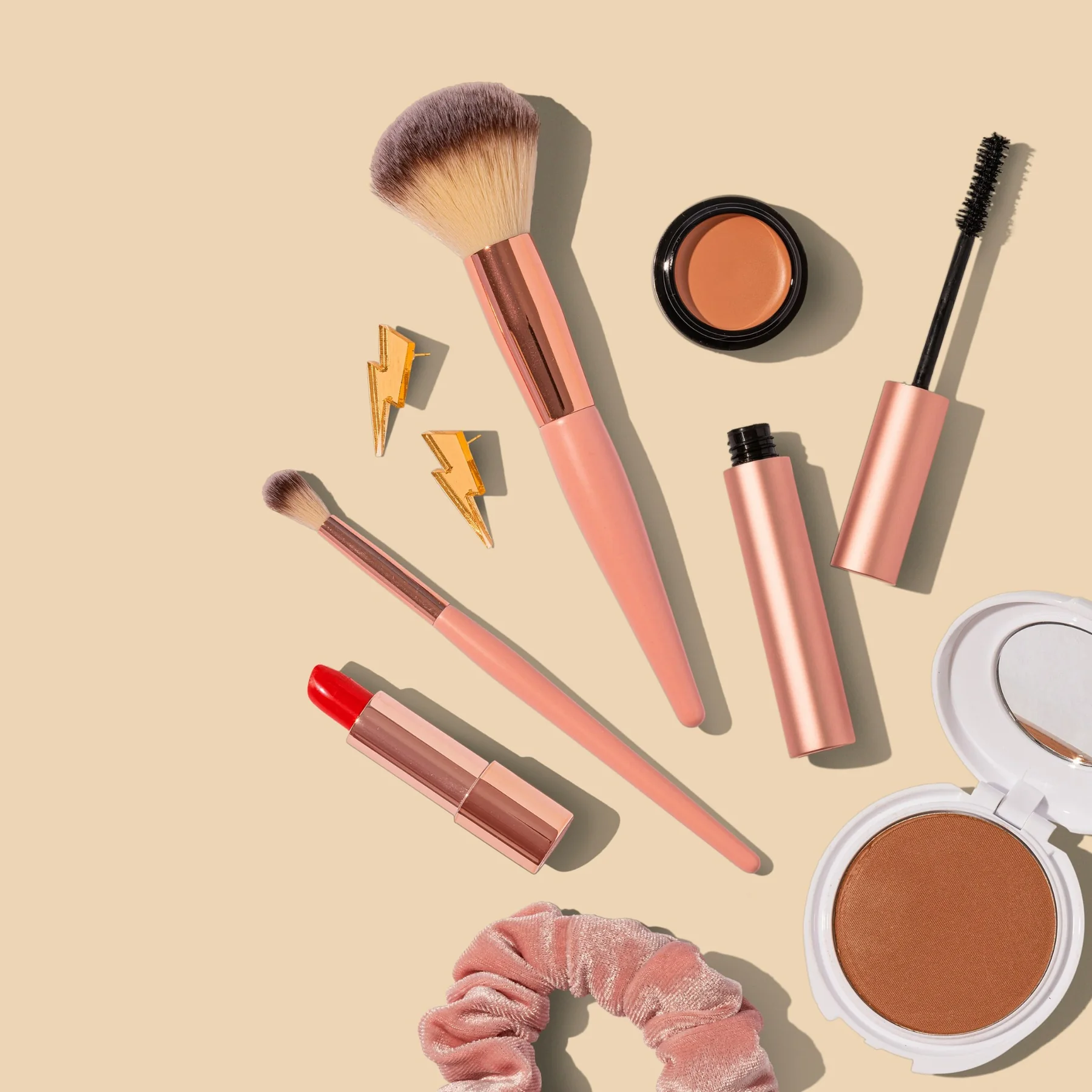 Flat lay of makeup brushes, lipstick, mascara and compact