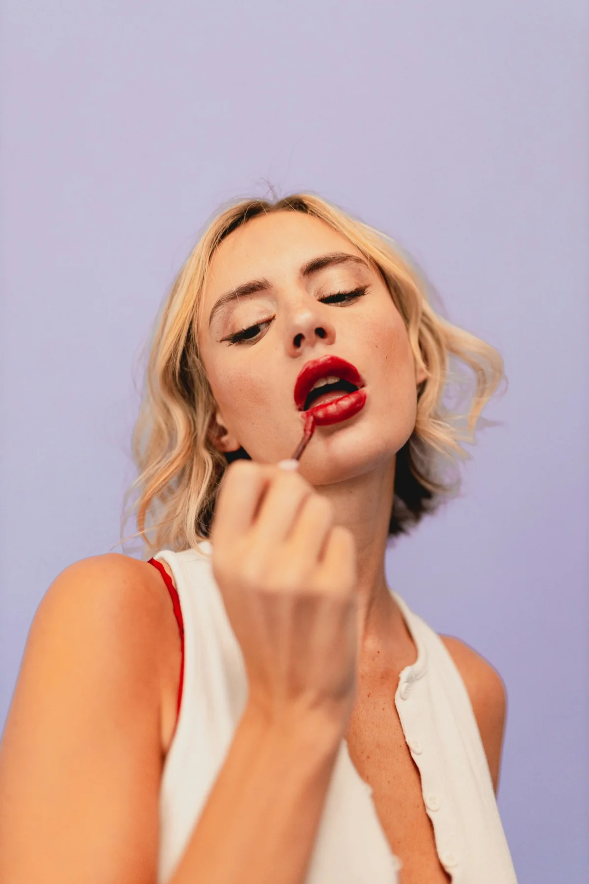 Editorial beauty portrait applying red lipstick